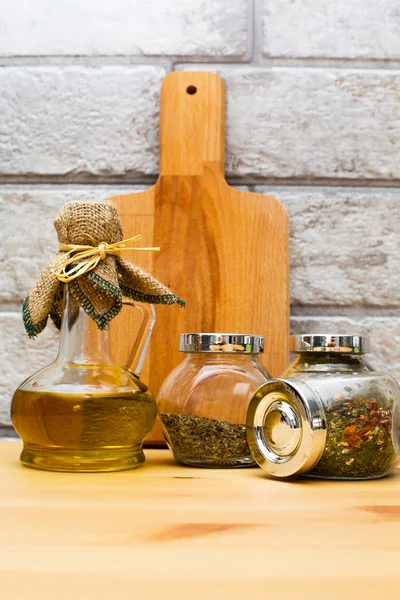 Jug of olive oil, cutting board and spices in the jars — Stock Photo, Image