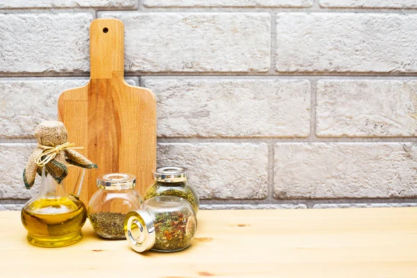 Jug of olive oil, cutting board and spices in the jars — Stock Photo, Image