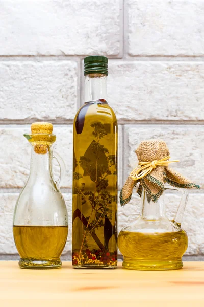 Three bottles of Olive oil on grey bricks background — Stock Photo, Image