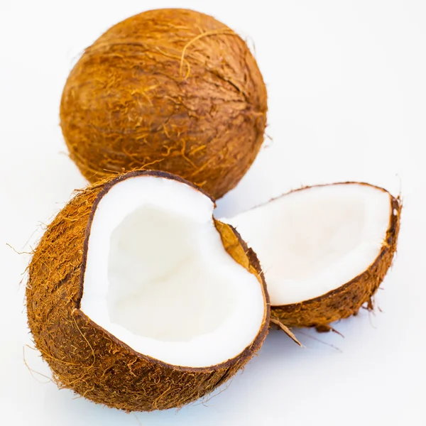 Fresco fechar partes de coco e frutas inteiras atrás no fundo branco — Fotografia de Stock