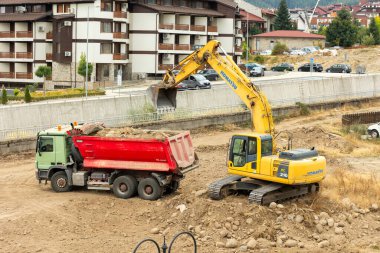 Bansko, Bulgaristan - 25 Eylül 2025: Sanayi kazıcısı bir çöp kamyonuna toprak yüklüyor