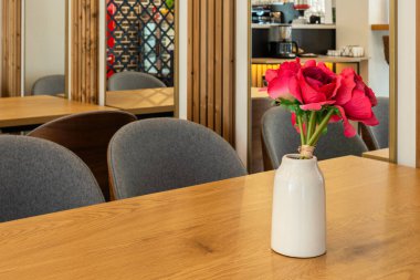 Ahşap masadaki siyah vazoda kırmızı gül çiçeği, dekorasyon ayrıntıları.