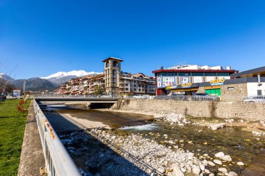 Bansko, Bulgaristan - 9 Nisan 2025: Glazne nehri, Bulgar kenti, otel evleri ve kar Pireni dağlarının zirveleri