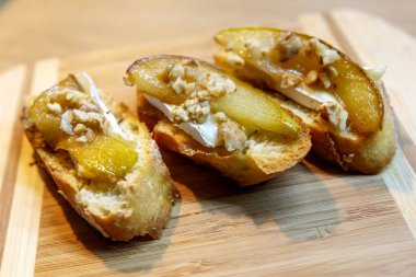 Beyaz peynirli birkaç armut bruschetta ve ahşap tahtada ceviz.