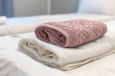 Beyaz ve pembe bej havlular otel müşterileri için misafir odasında yatağın üzerine katlanmış.