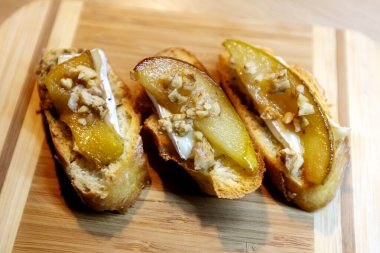 Beyaz peynirli birkaç armut bruschetta ve ahşap tahtada ceviz.