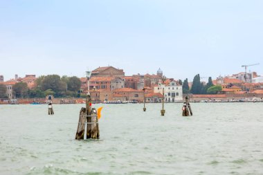 Venedik, İtalya - 1 Ekim 2024 Ufukta Murano adası ve Venedik Gölünde seyrüsefer ahşap kutuplar