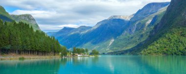 Norveç, Olden yakınlarındaki dağlarla, kamp alanlarıyla ve yemyeşil yeşilliklerle çevrili turkuaz Norveç fiyortunun nefes kesici panoramik manzarası.