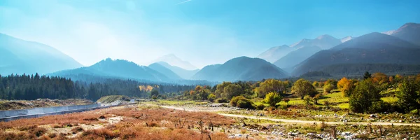 Fond panoramique automnal vibrant avec des arbres verts, rouges, jaunes et des sommets de montagne colorés — Photo