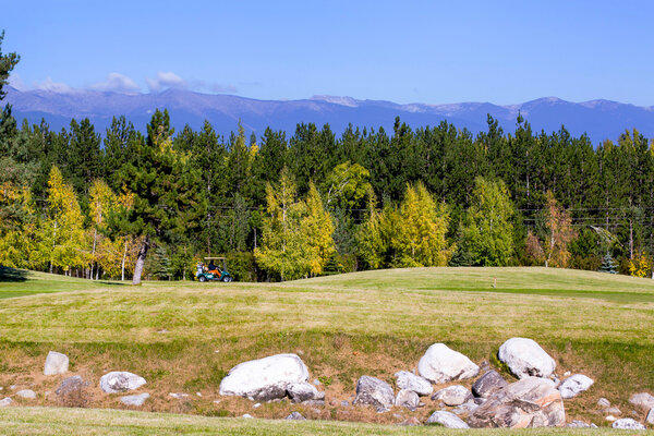 Pirin Golf Club panorama, golf cart,  green grass field, colorful trees, blue sky