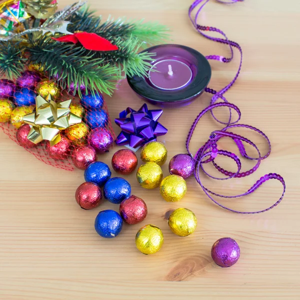Різдвяні святкові прикраси, фіолетові та жовті золоті солодкі цукерки, свічки, гілка соснового дерева — стокове фото
