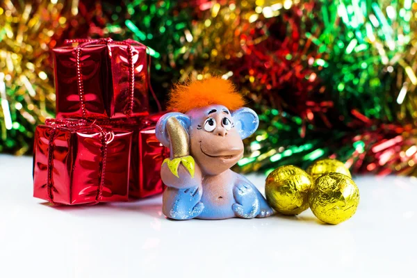 Capodanno sfondo vacanza con capelli rossi scimmia, regali, dolci gialli e decorazioni glitter — Foto Stock