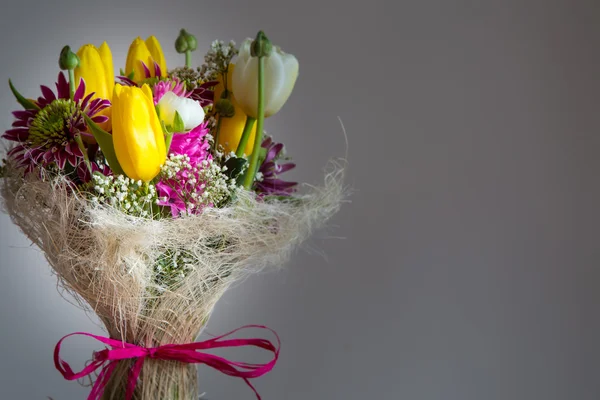 Barevné kytice žlutých tulipánů, různé jarní květy na šedém pozadí — Stock fotografie