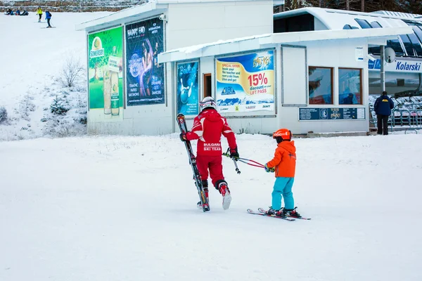 Het kind leren skiën en instructeur op de helling in Bansko, Bulgarije — Stockfoto