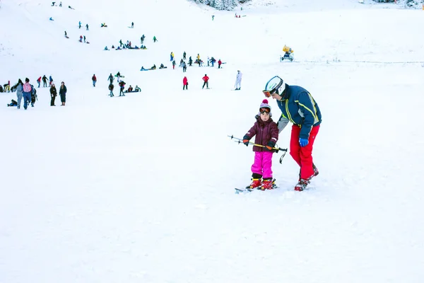 Дитина вчимося лижних і людина на схилі в Банско, Болгарія — стокове фото