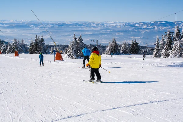 Лыжный склон, люди катаются на лыжах с холма, вид на горы — стоковое фото