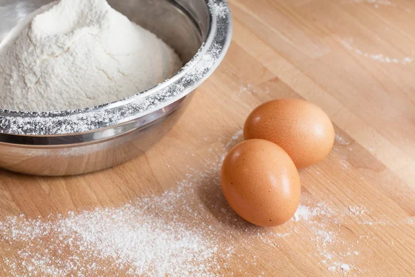 在碗里的面粉和木桌背景上的两个鸡蛋 图库照片