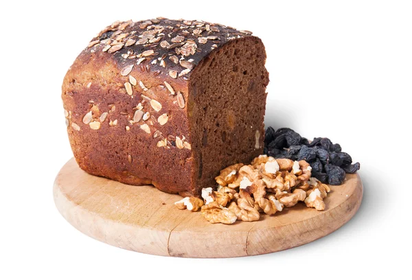 Bread with seeds on wooden board with raisins and nuts — Stock Photo, Image