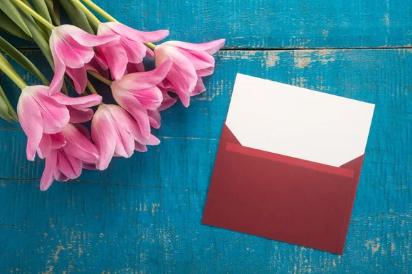 Flowers and envelope on a wooden background — Stock Photo, Image