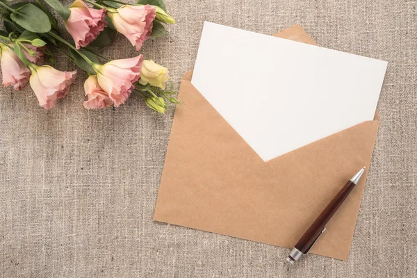 Flores, envelope e caneta em um fundo cinza — Fotografia de Stock