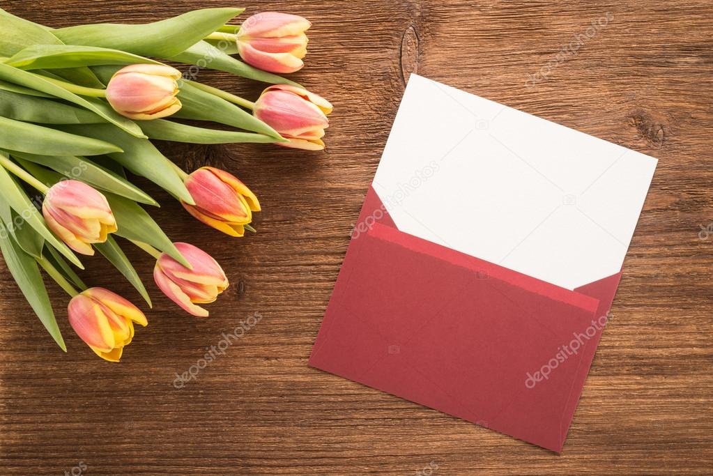 Flowers and envelope on wooden background