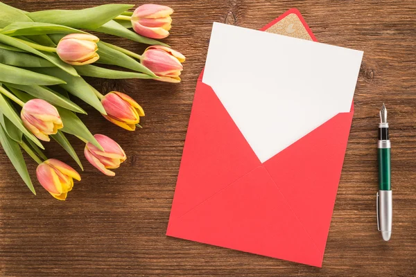 Flores, envelope e caneta sobre fundo de madeira — Fotografia de Stock