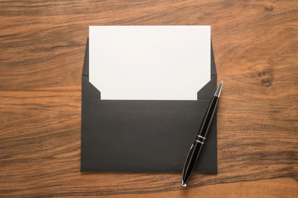 Black envelope with white paper and pen — Stock Photo, Image