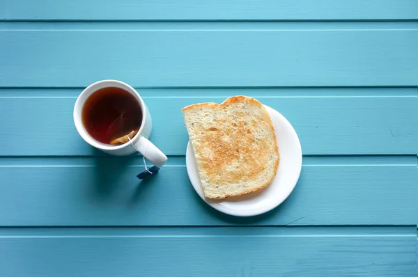 Desayuno por la mañana con tostadas y té sobre fondo azul, centrado en tostadas — Foto de Stock