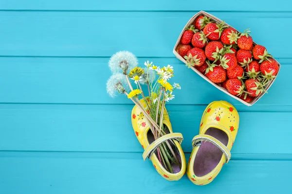 Zomer achtergrond met aardbei, bloemen en kleine schoenen — Stockfoto