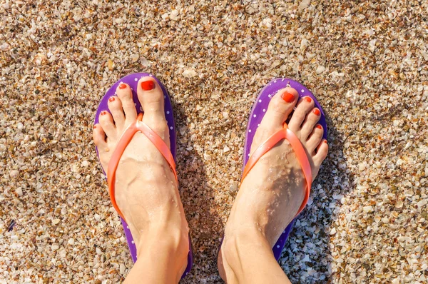 Female legs wearing flip flops near sea. top view — Stock Photo, Image