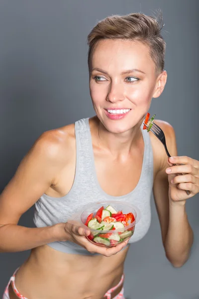 Портрет привлекательного вида спорта кавказская улыбающаяся женщина ест салат — стоковое фото