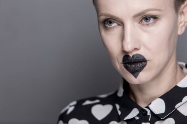 Alışılmadık makyajlı, dudaklarında siyah bir kalp olan güzel bir genç kadın. siyah ve beyaz