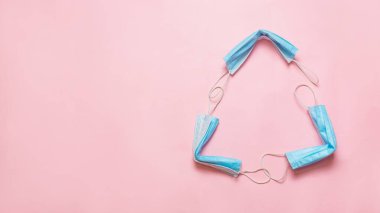 Kullanılmış tıbbi maskeden yapılmış geri dönüşüm işareti. Geri dönüşüm kutusuna tıbbi maske takıyor. Kullandıktan sonra mavi maskeler. Tıbbi maskeler