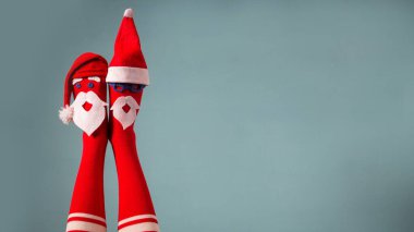 Güzel Noel bacakları. Suratlı çoraplar ve Noel Baba şapkaları giyen komik kadın bacakları. Noel partisi, bayram kutlaması, Noel indirimi.
