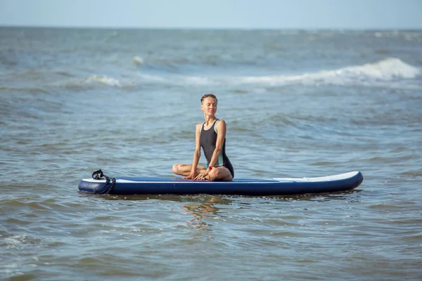 Frau Praktiziert Morgens Yoga Auf Dem Paddelbrett Auf Welligem Meer — Stockfoto