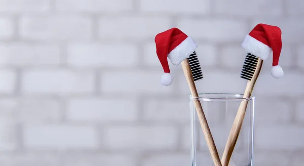 Two Toothbrushes Glass Wearing Santa Hats Brick Wall Background Bamboo — Stock Photo, Image