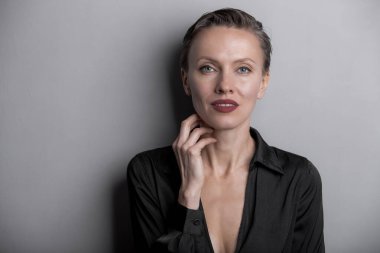 İpek takım elbiseli, kısa saçlı, zarif görünümlü bir kadın portresi.