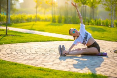 Güzel bir kadın yaz parkında yoga egzersizleri yapıyor.