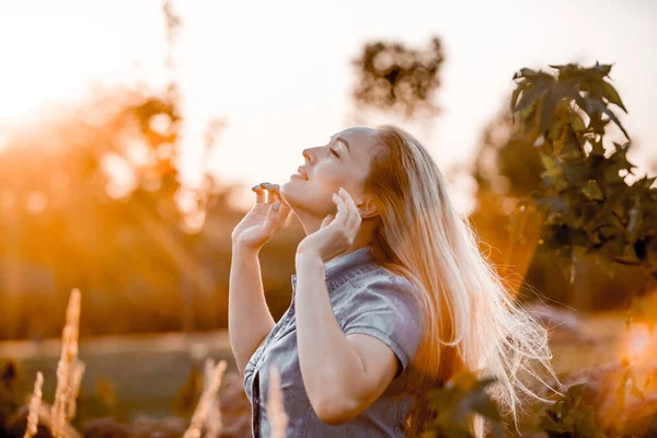Uçan saçlı güzel bir kadın gün batımı ışığında yürüyor, tonlu bir görüntü.