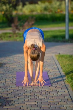 Güzel bir yaz ya da bahar parkında yoga yapan genç bir kadın. Uyum, meditasyon ve seyahat konsepti. Sağlıklı yaşam tarzı
