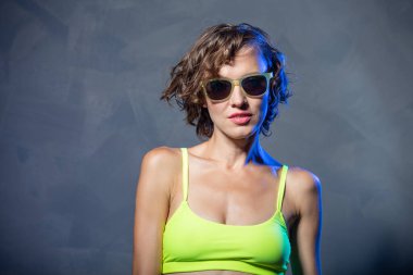 Gri arka planda parlak mayo giyen genç bir kadın. Spor, diyet, cilt ve vücut bakımı