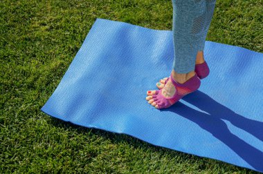 Sabahları yoga. Genç kadın yeşil çimlerde yoga minderinde pratik yapıyor.