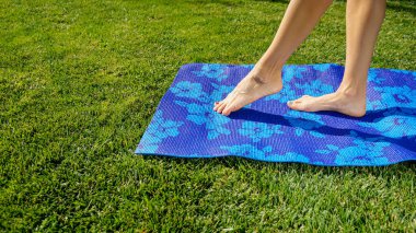 Sabahları yoga. Genç kadın yeşil çimlerde yoga minderinde pratik yapıyor.