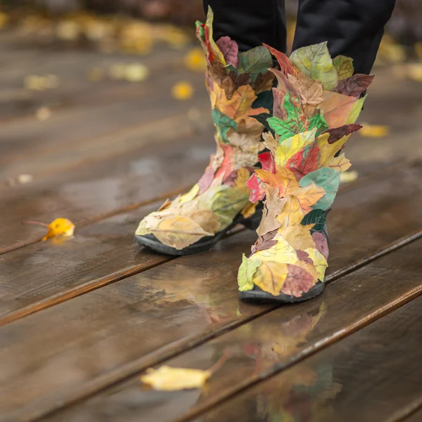 Herbstbeine in lustigen Stiefeln aus fallendem Laub — Stockfoto