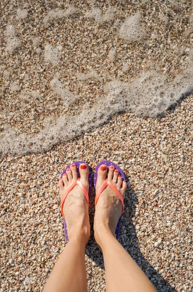 Female legs wearing flip flops near sea — Stock Photo, Image