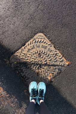 Corbridge, Northumberland, İngiltere - 21 Kasım 2025: Klasik görüntü koşucusu bacakları ve metal kanalizasyon kapağı