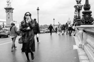 Paris, Fransa - 15 Ekim 2025 Paris Köprüsü 'nde yürüyen deri yağmurluklu güzel bir kadın. Paris sokak modası