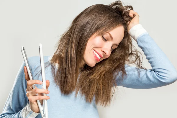 Femme drôle avec les cheveux salissants tenant fers à lisser — Photo