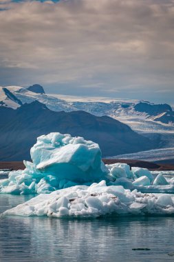 İzlanda 'daki Jokulsarlon Buzul Gölü' nde yüzen buzdağları ve arka planda buzul.