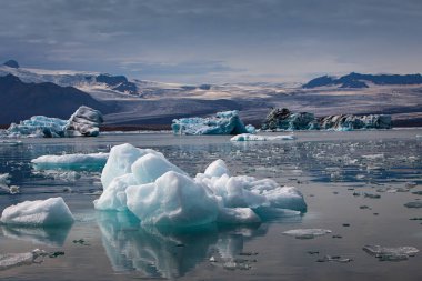 İzlanda 'daki Jokulsarlon Buzul Gölü' nde yüzen buzdağları ve arka planda buzul.